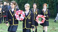 Children lay handmade wreaths at remembrance service in school grounds