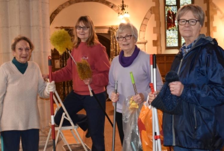 Volunteers clean church with brushes and beeswax