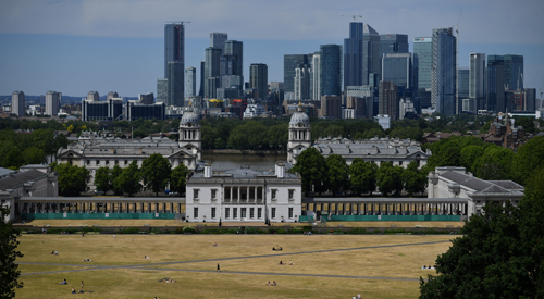 People relax as they take in the view of the London City sky line from Greenwich Park.